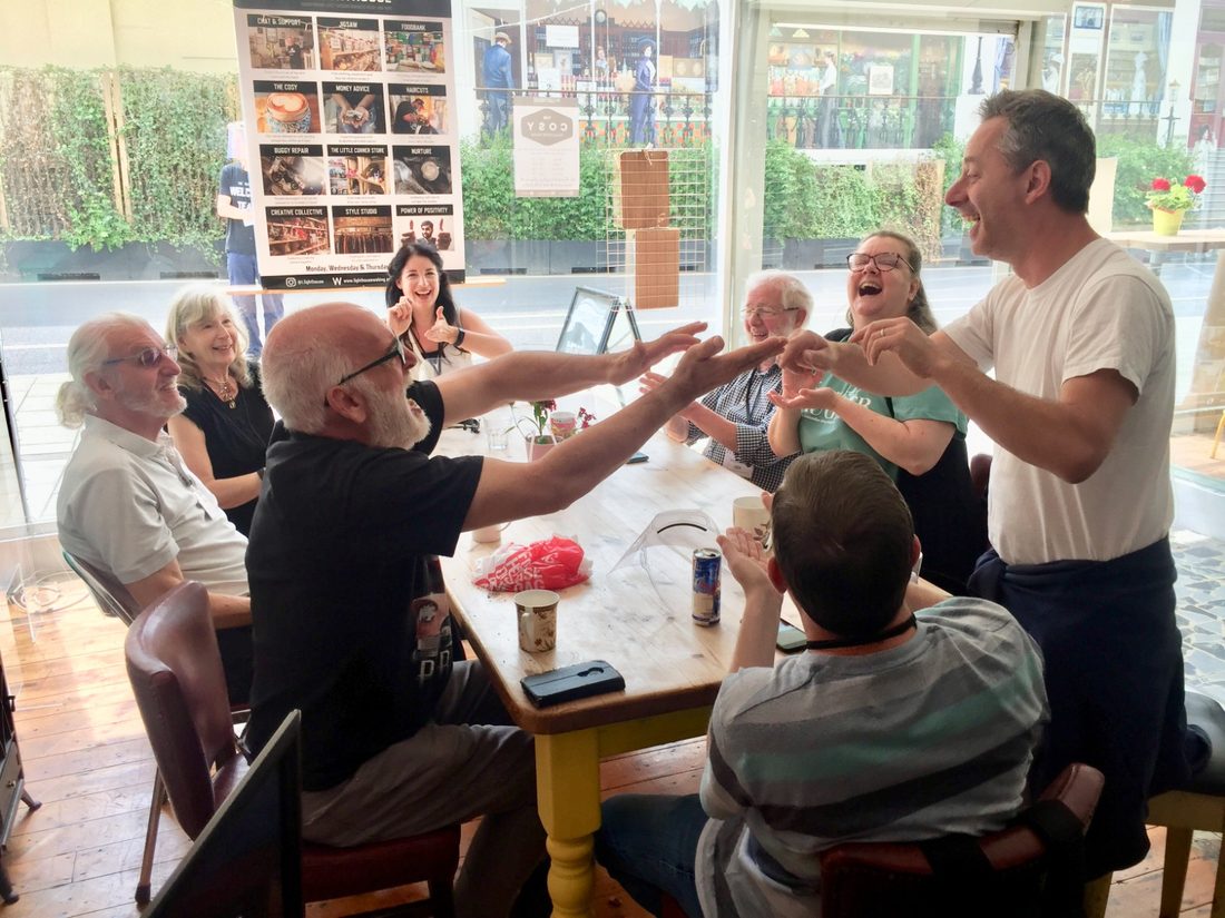 Jo-Dee Walmsley laughing with a small group around a table at a Lighthouse Woking community session.