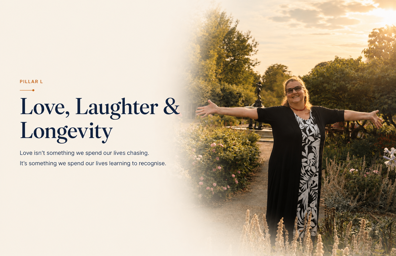 Jo-Dee Walmsley standing with her arms flung wide open in a rose garden at golden hour, smiling, with a garden fountain and trees behind her.