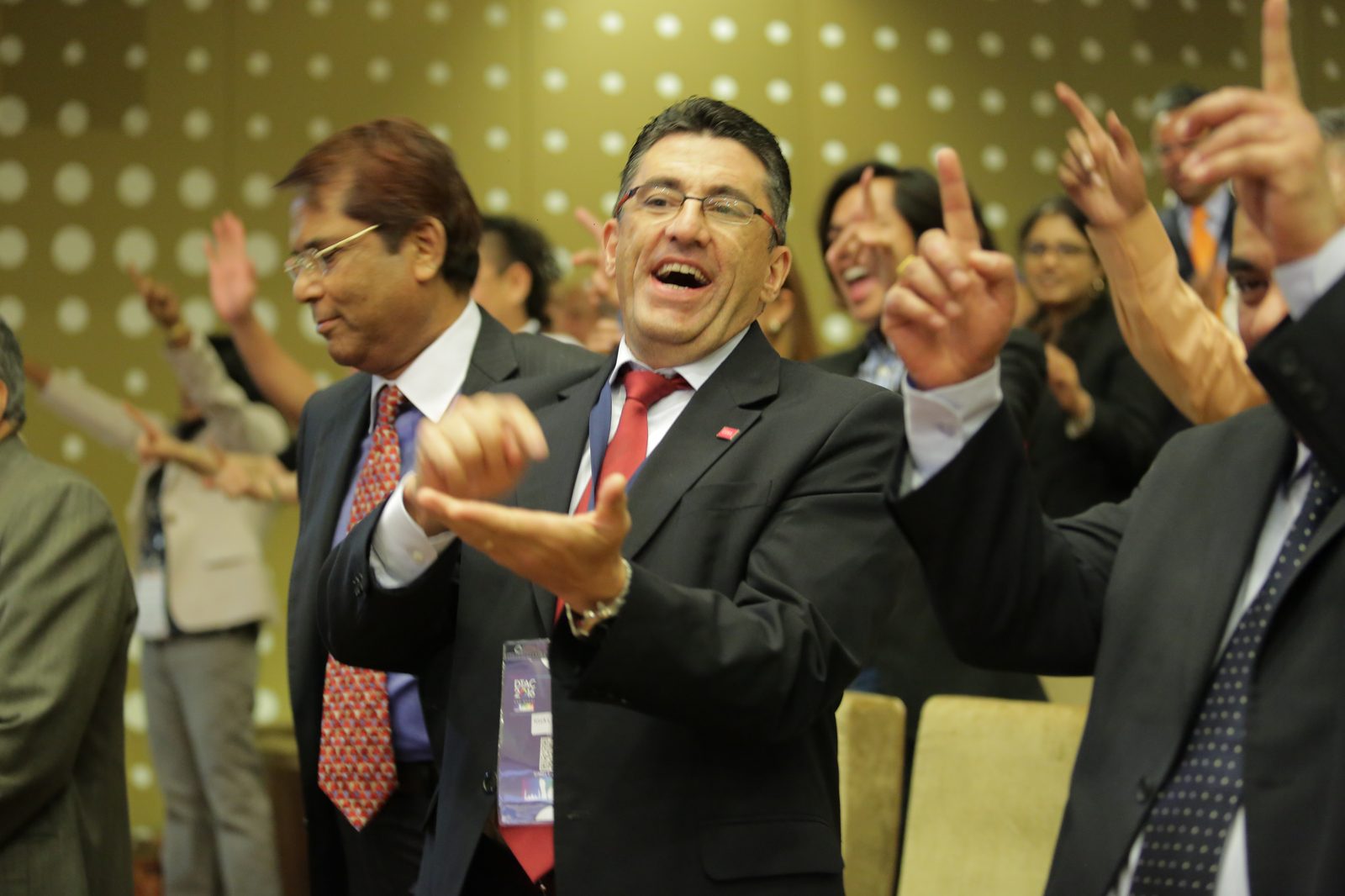 Delegates cheering and pointing with energy during an interactive session led by Jo-Dee Walmsley.